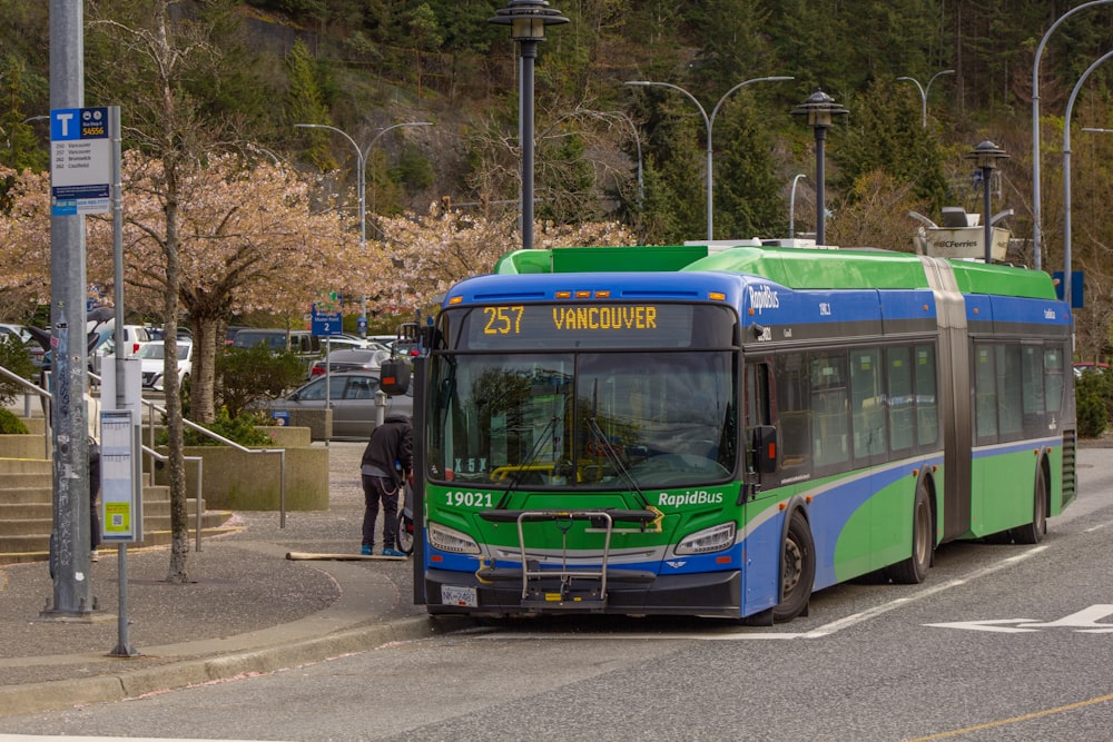 a green and blue bus driving down a street