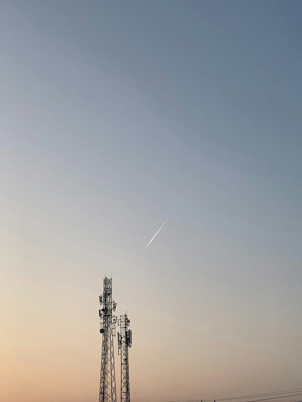 a cell tower with a plane flying in the sky