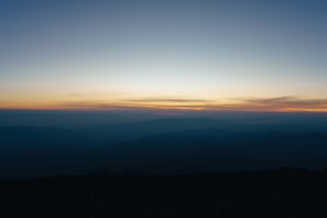 the sun is setting over a mountain range