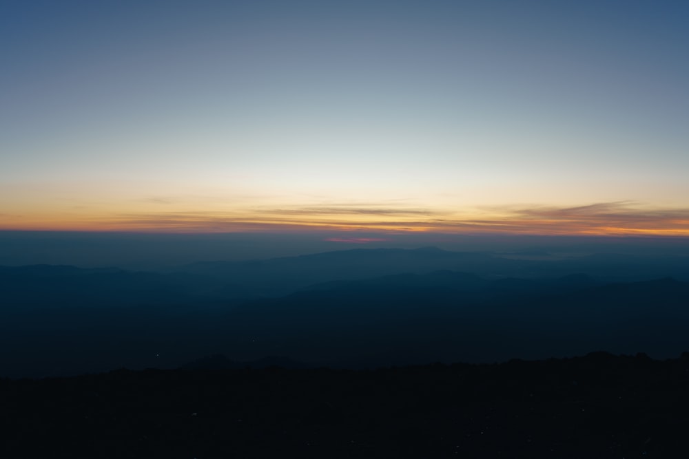 the sun is setting over a mountain range