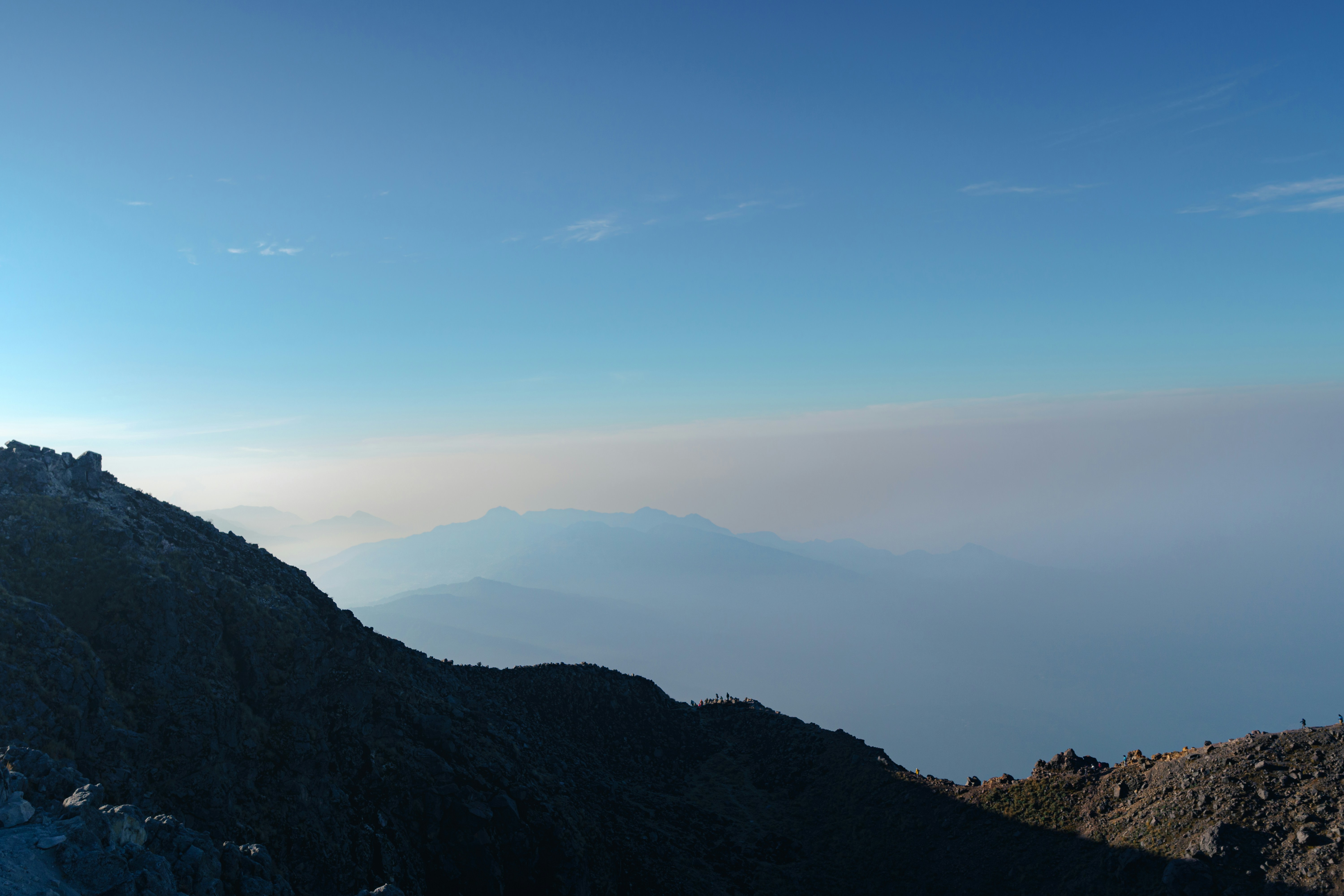 a person standing on top of a mountain with a sky background