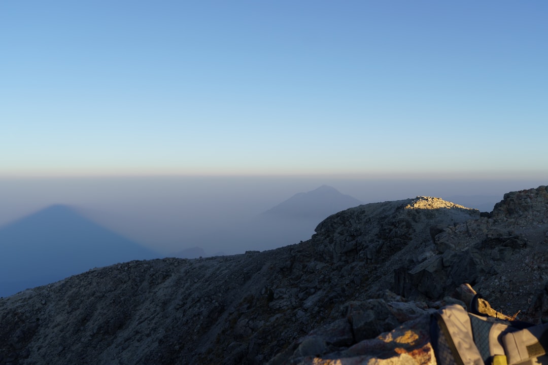 a person standing on top of a rocky mountain, Photographic series documenting the adventure of climbing Tajumulco Volcano, San Marcos, Guatemala. Showcasing diverse landscapes, sunsets, mountain terrains, plants, and fellow adventurers. Focusing on outdoor sports and the beauty of nature through adventure and travel photography.
