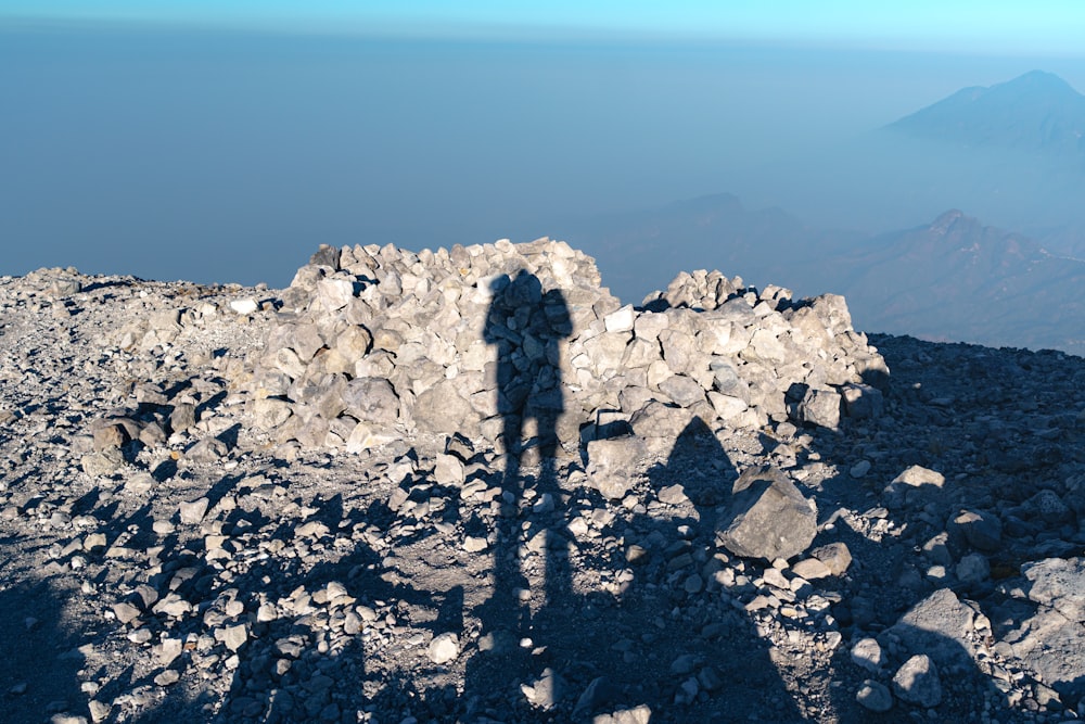a shadow of a person standing on top of a mountain