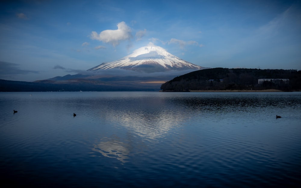 a snow covered mountain sitting above a lake