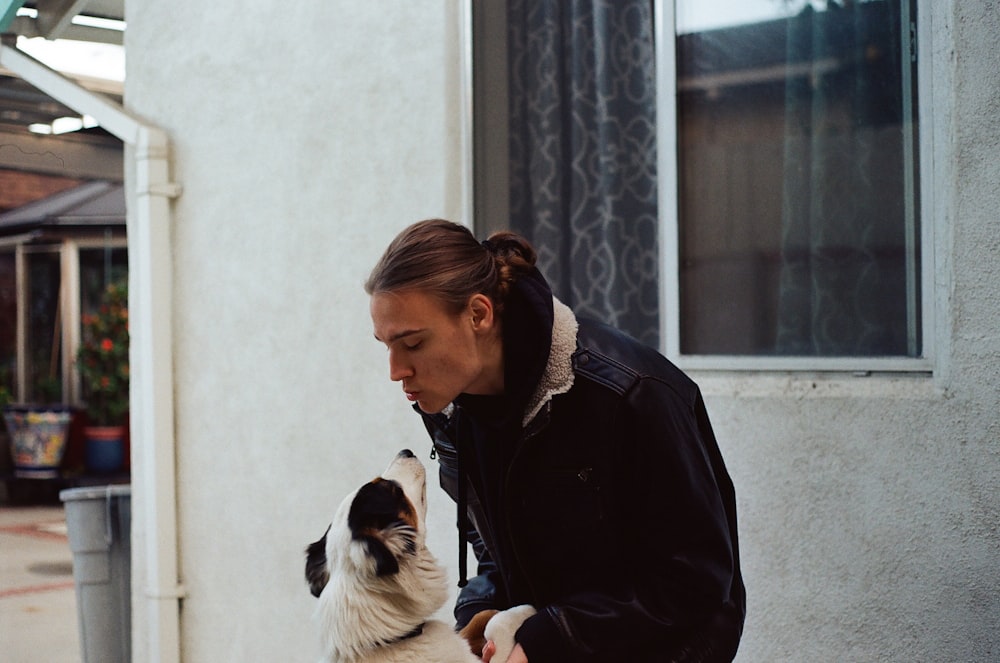 a woman standing next to a white and black dog