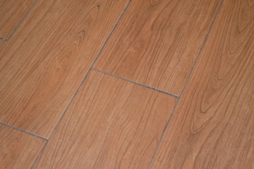 a close up of a wooden floor with a white cat laying on it