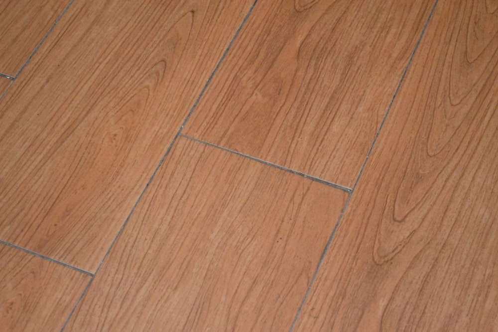 a close up of a wooden floor with a white cat laying on it