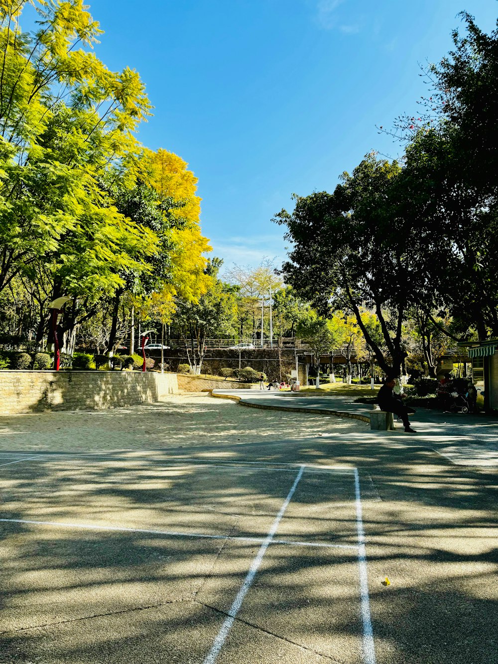 a tennis court surrounded by trees and a bridge