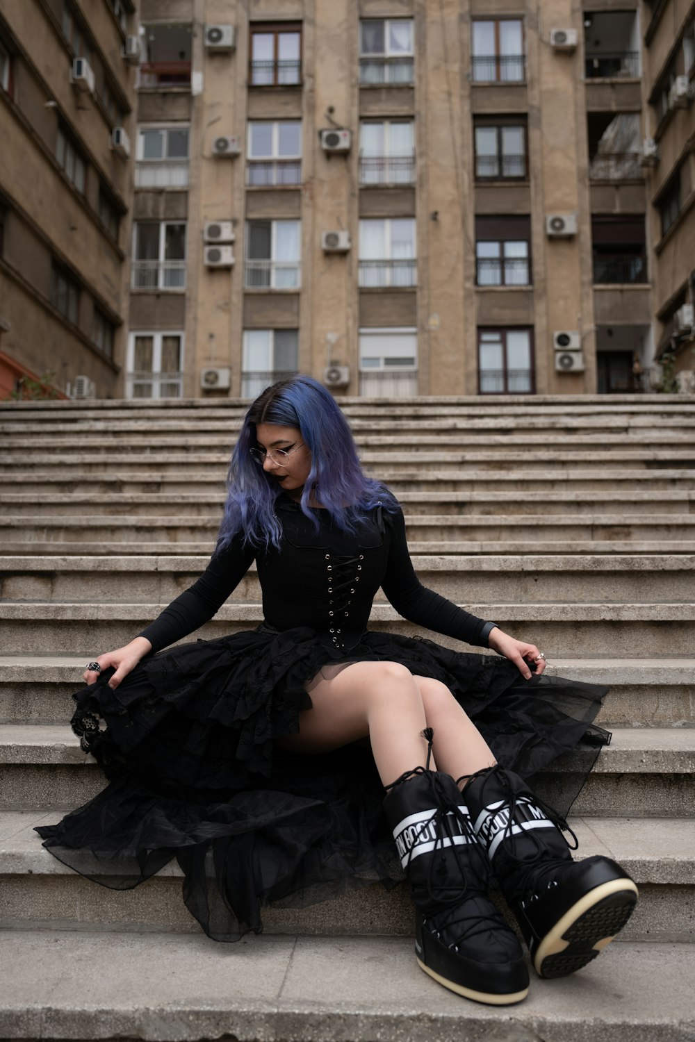 a woman with blue hair sitting on some steps