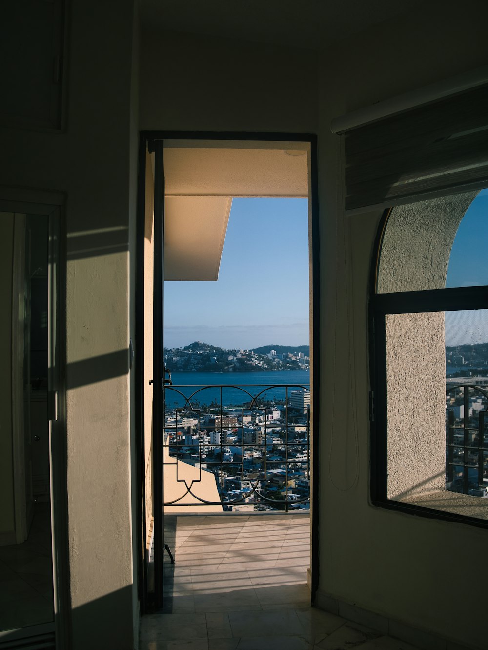 an open door leading to a balcony with a view of a city