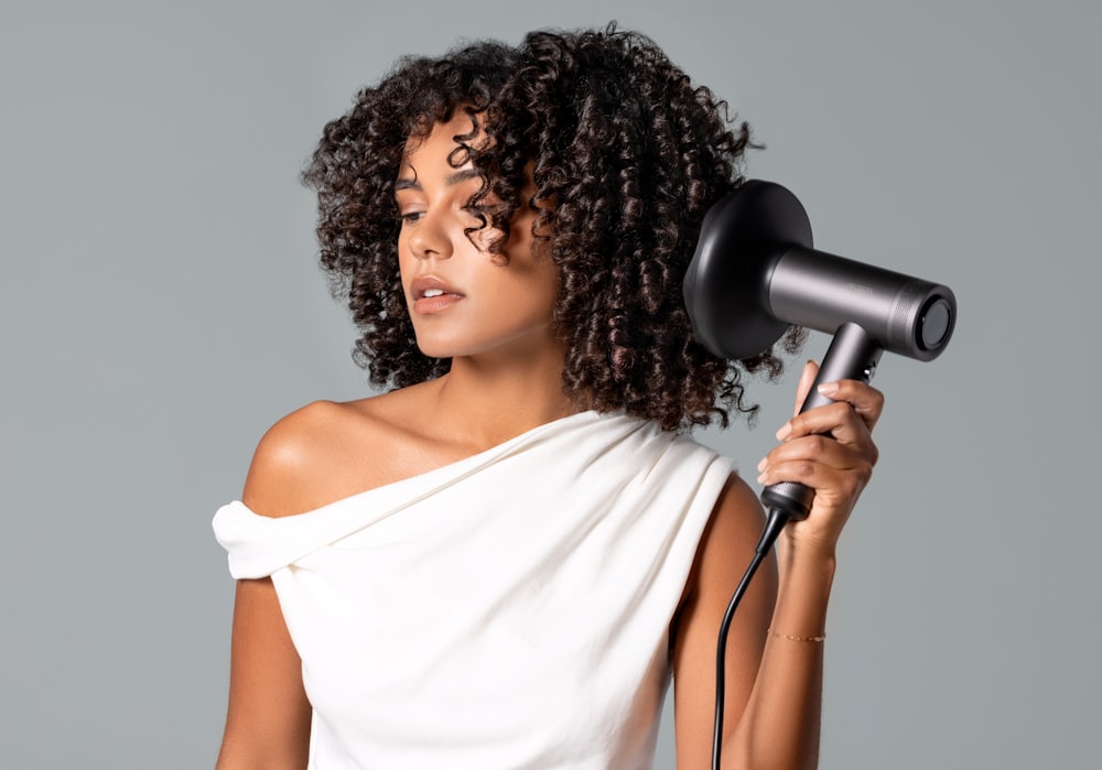 a woman blow drying her hair with a hair dryer