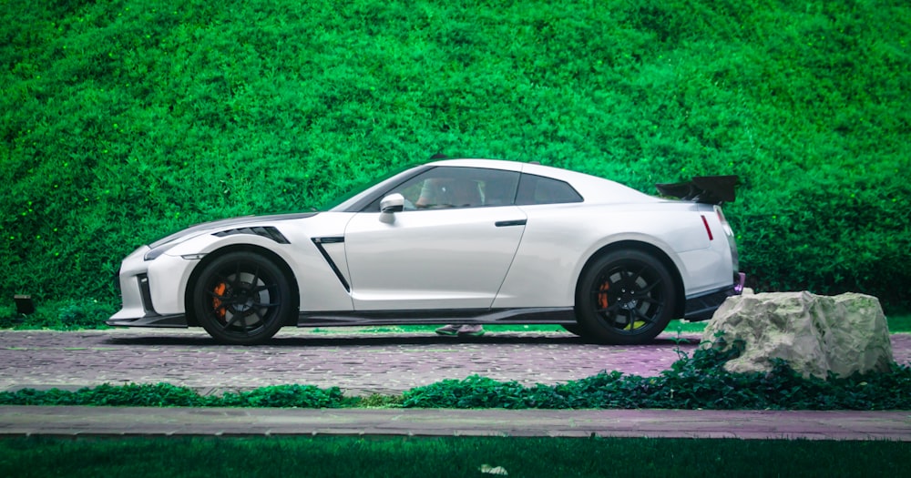 a white sports car parked in front of a green wall