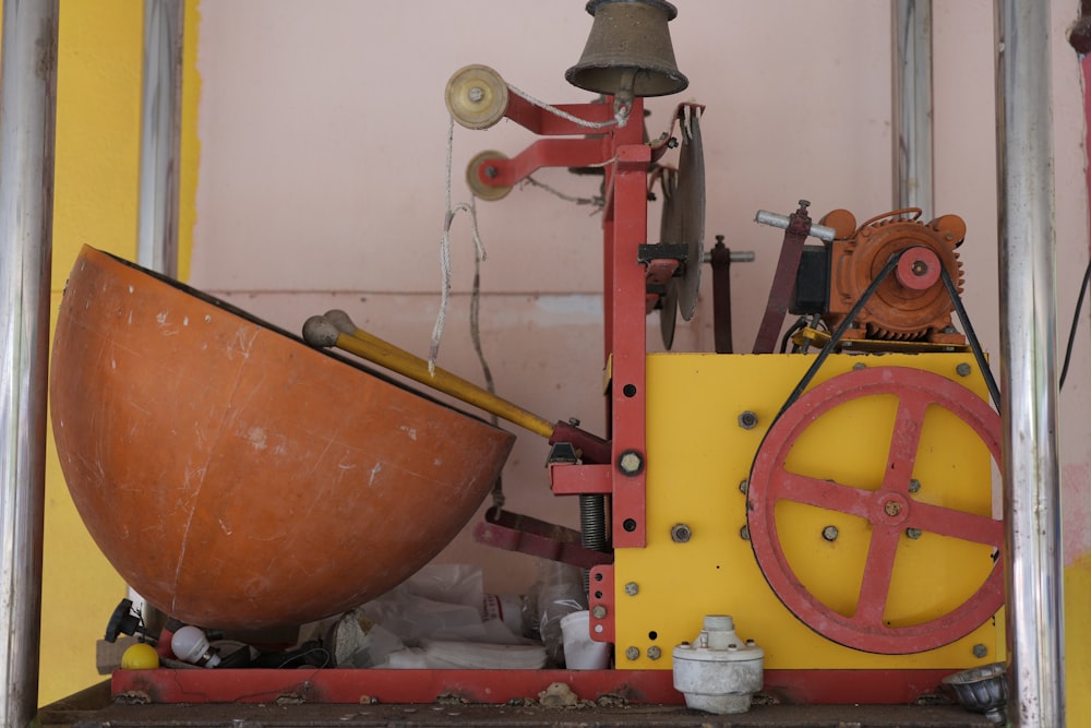 a yellow and red machine with a bell on top of it