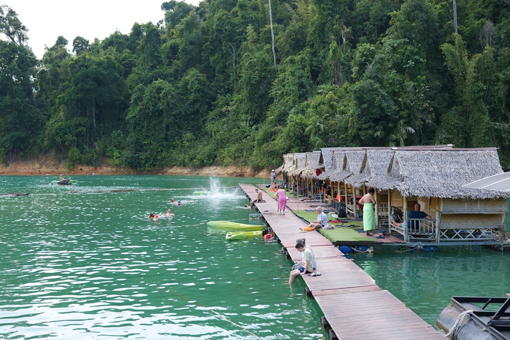 a group of people standing on a pier next to a body of water