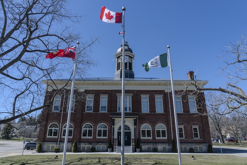 three canadian flags flying in front of a building