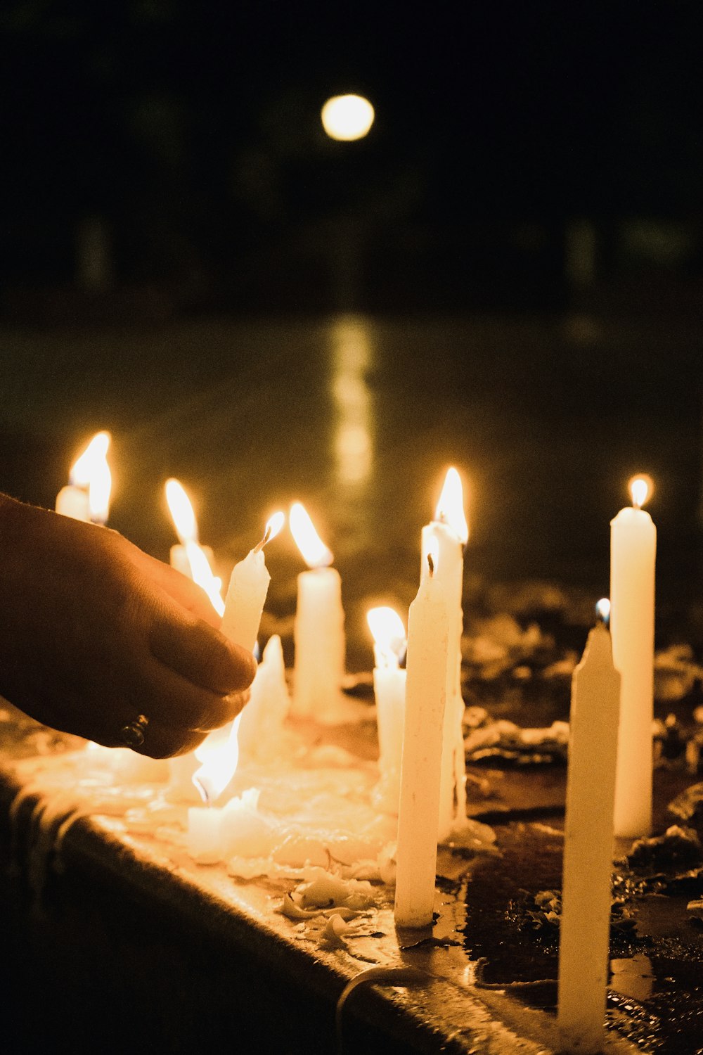 a person lighting candles on a table in the dark
