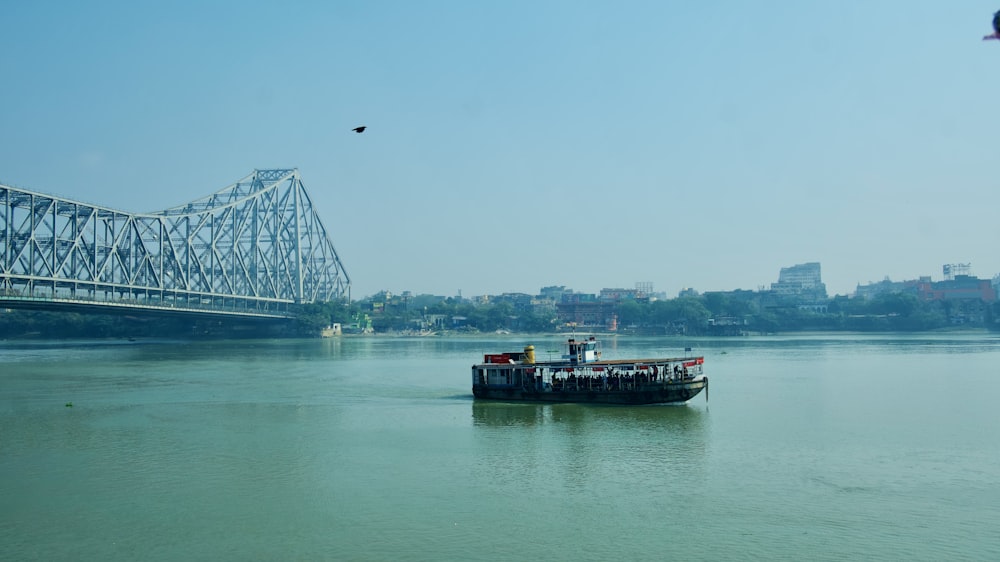 a boat floating on top of a river next to a bridge