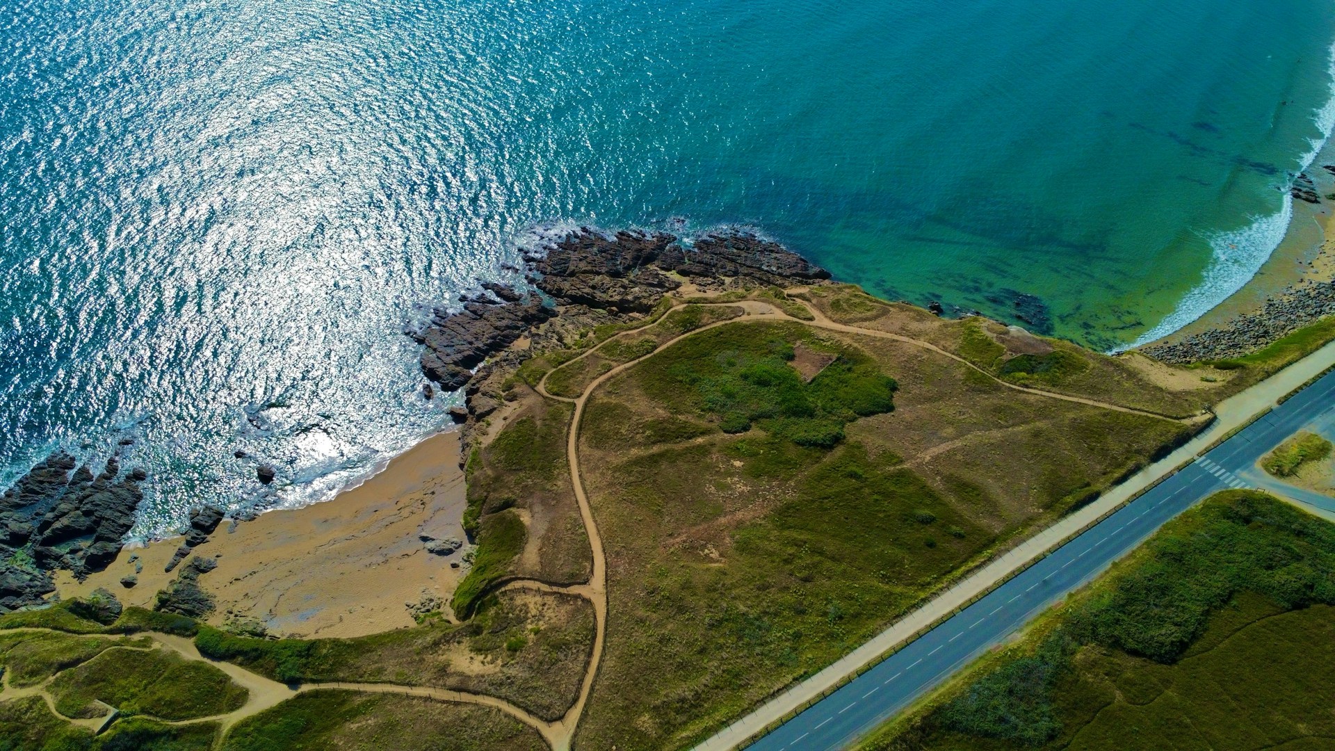 an aerial view of a road near the ocean