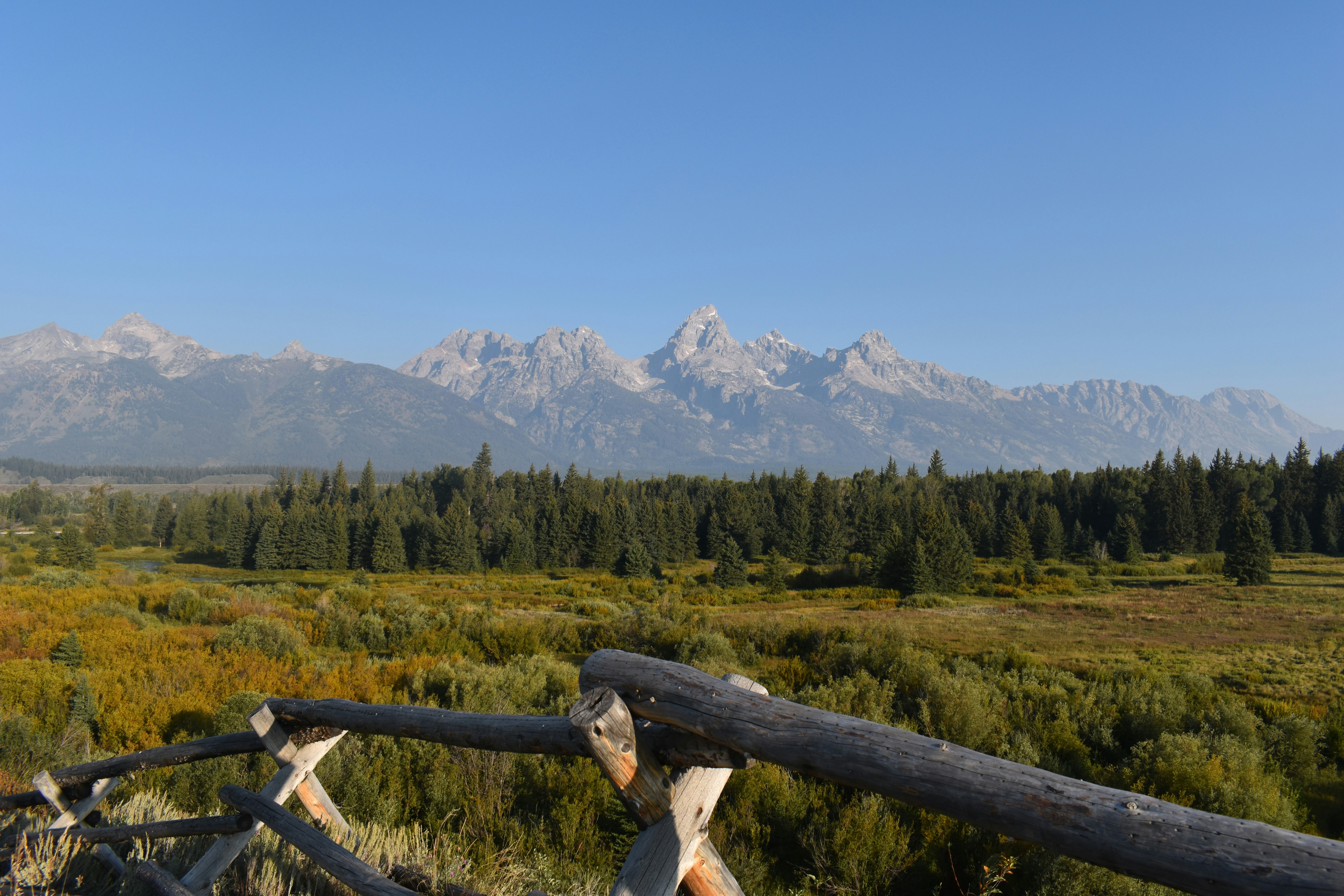 a view of a mountain range from a wooden fence