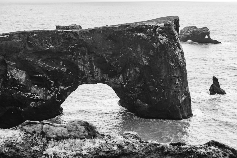 a black and white photo of a rock formation in the ocean