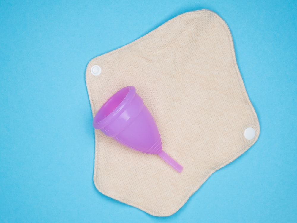 a purple plastic cup sitting on top of a cloth