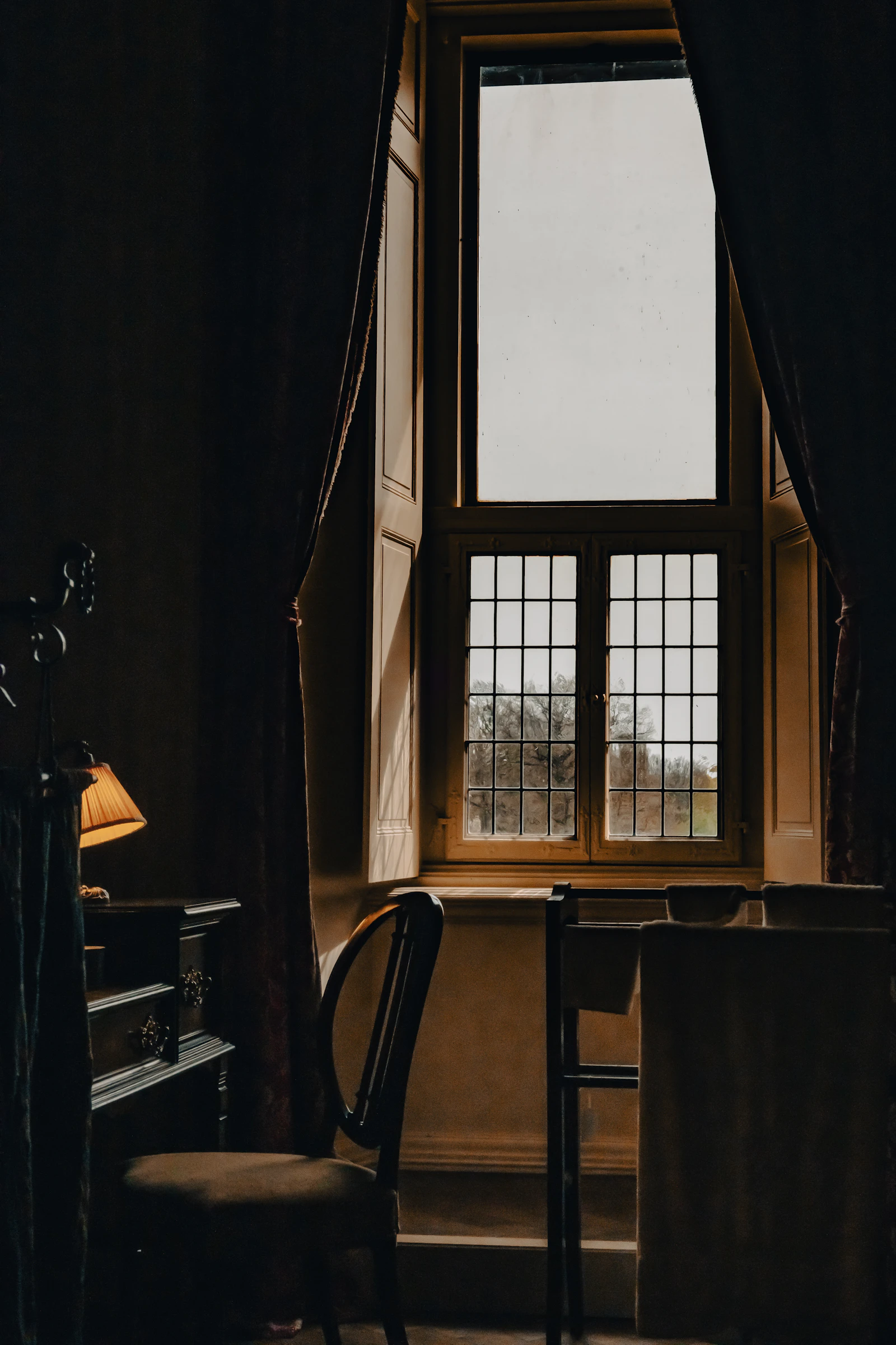 A dark room with a chair and a window