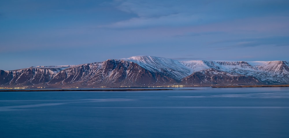 a large mountain covered in snow next to a body of water