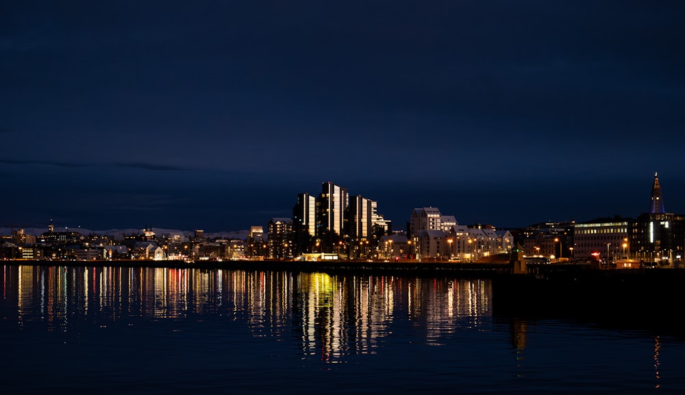 a city is lit up at night by the water