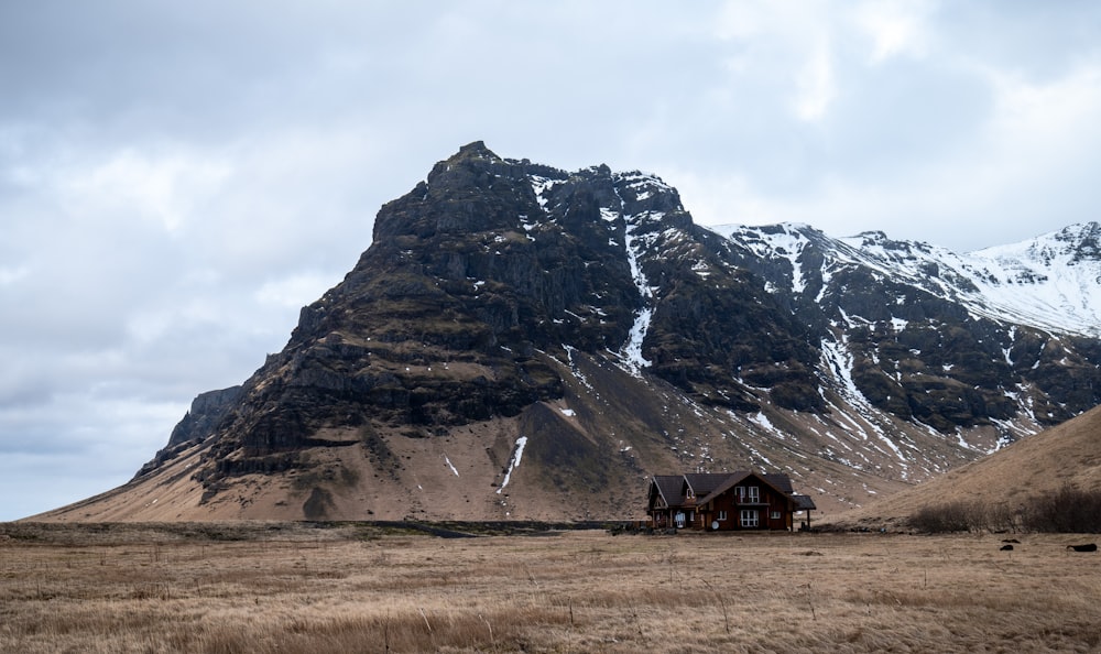 a house in the middle of a field with a mountain in the background
