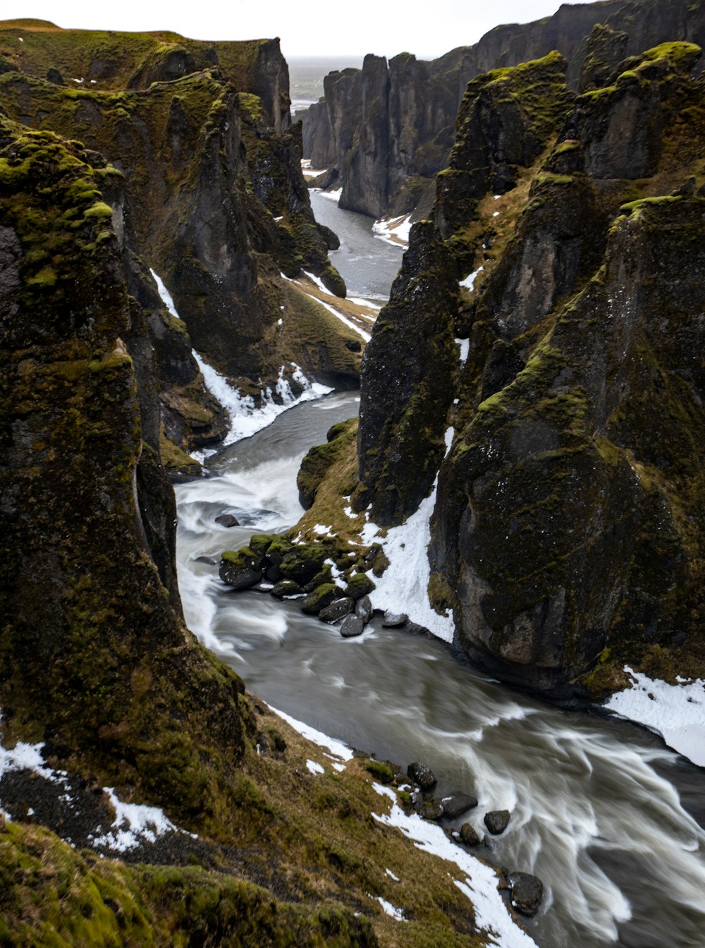 a river flowing between two rocky mountains covered in snow