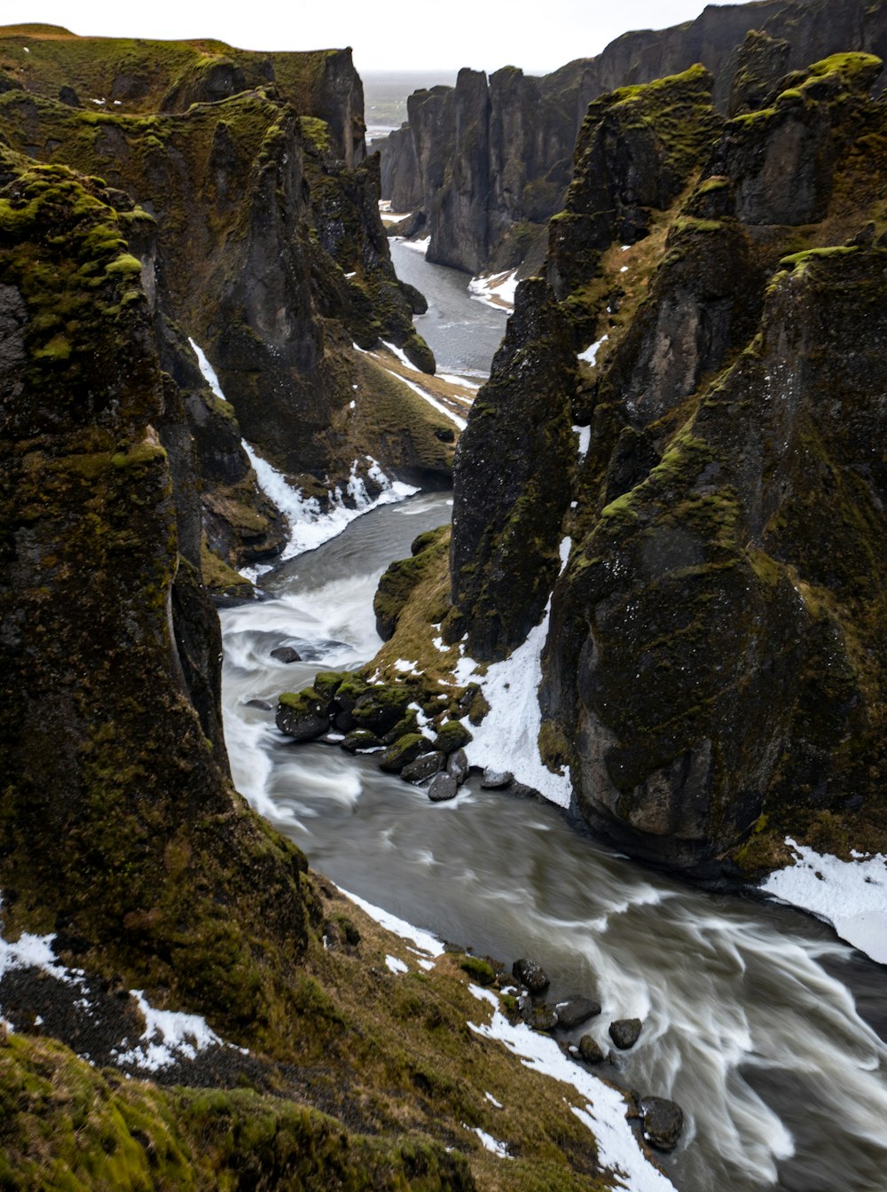 ein Fluss, der zwischen zwei felsigen, schneebedeckten Bergen fließt