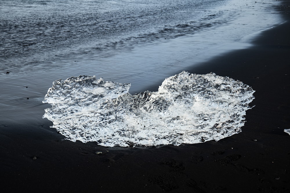 a piece of ice on a beach next to the ocean