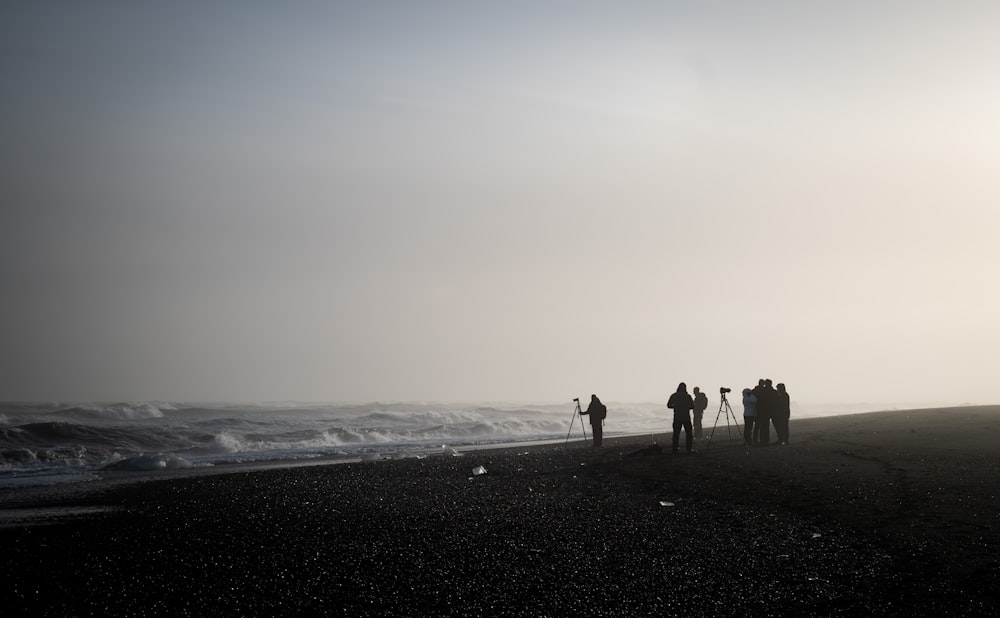 a group of people standing on top of a beach