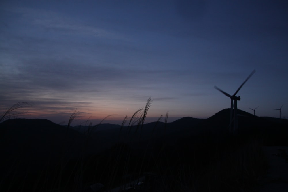 a wind turbine is silhouetted against a twilight sky