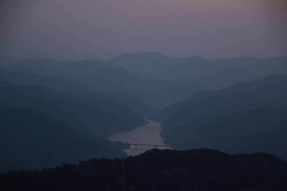 the sun is setting over the mountains and a body of water