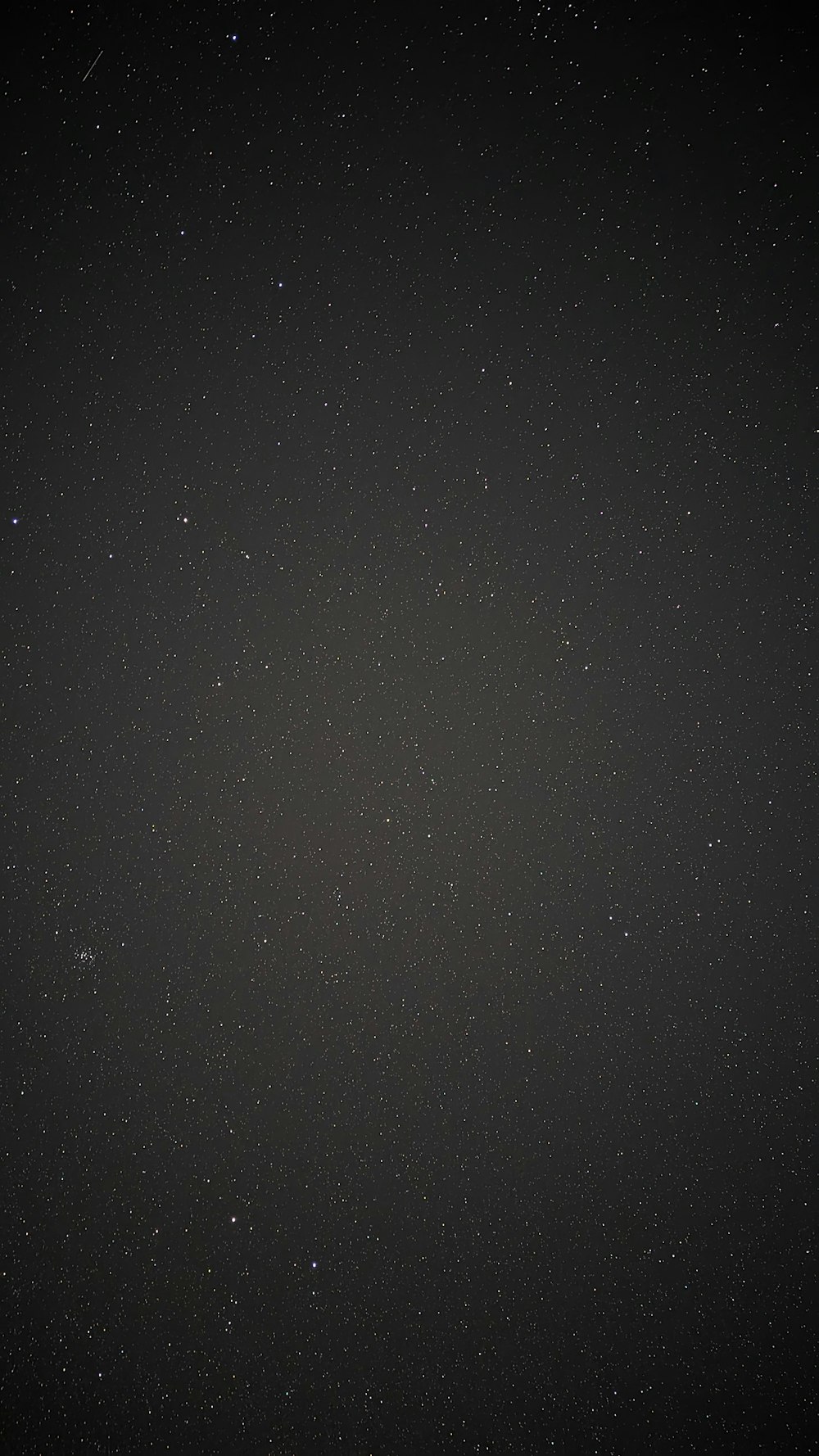 a dark night sky with stars and a plane in the distance