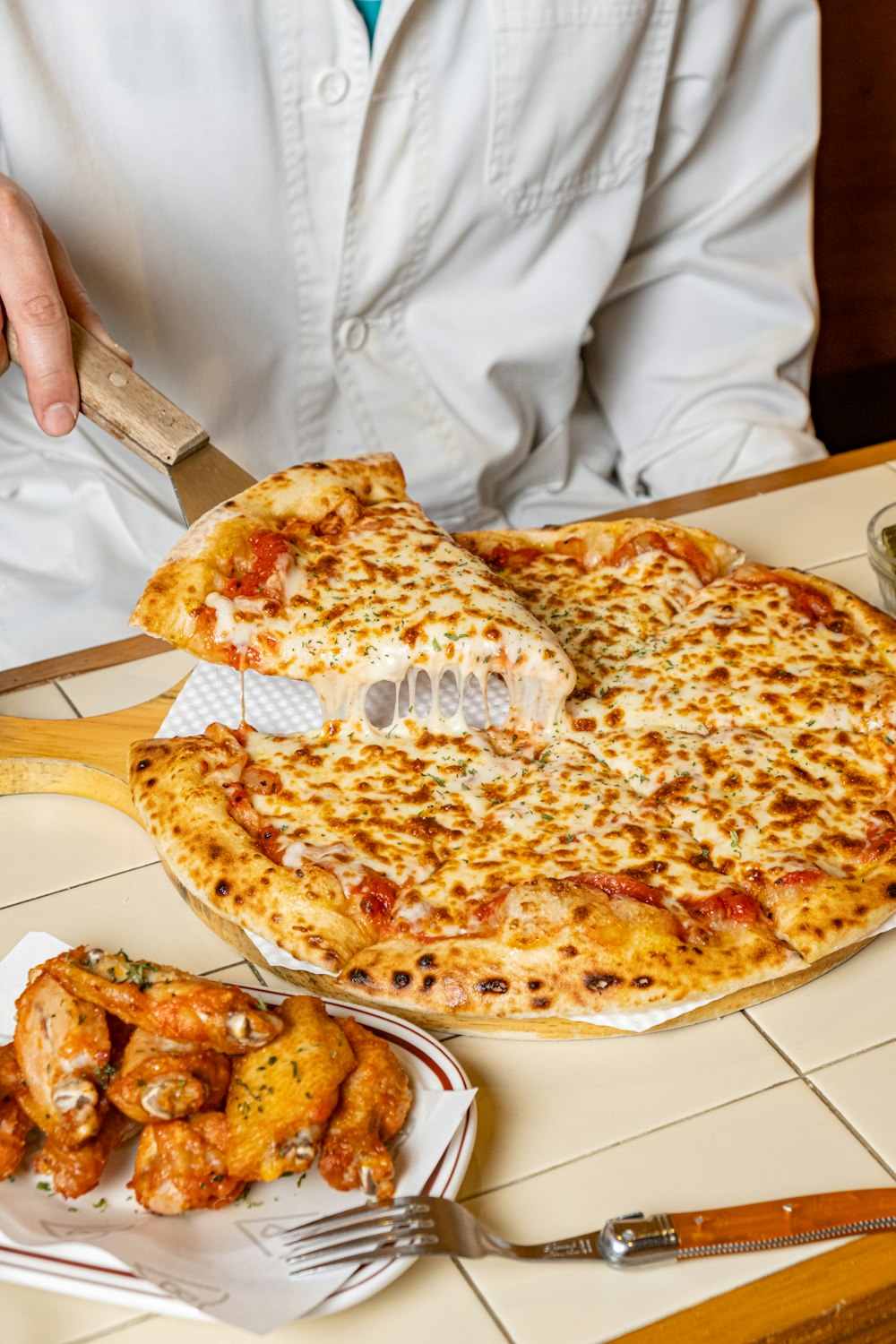 a person cutting a pizza with a knife and fork