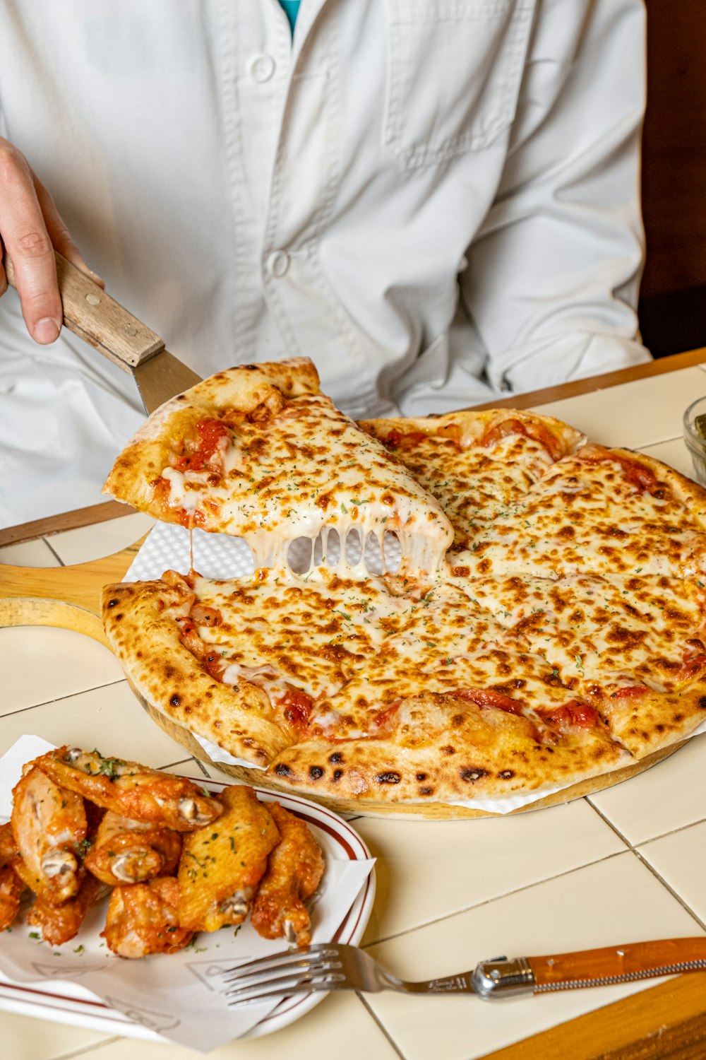 uma pessoa cortando uma pizza com uma faca e garfo