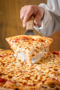 a person cutting a slice of pizza with a pizza cutter