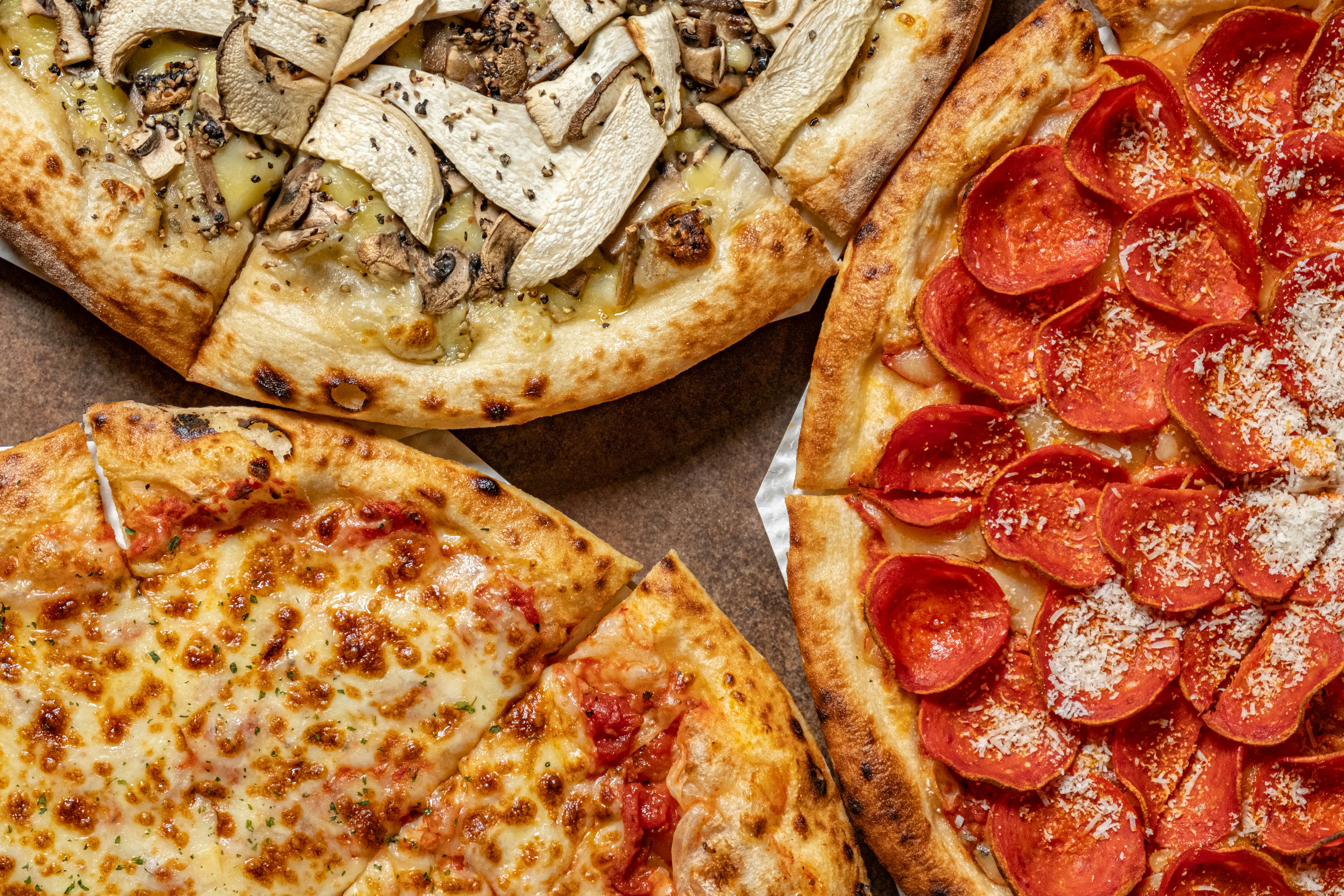 three pizzas side-by-side: New York, Chicago, and Detroit style - pizza pans