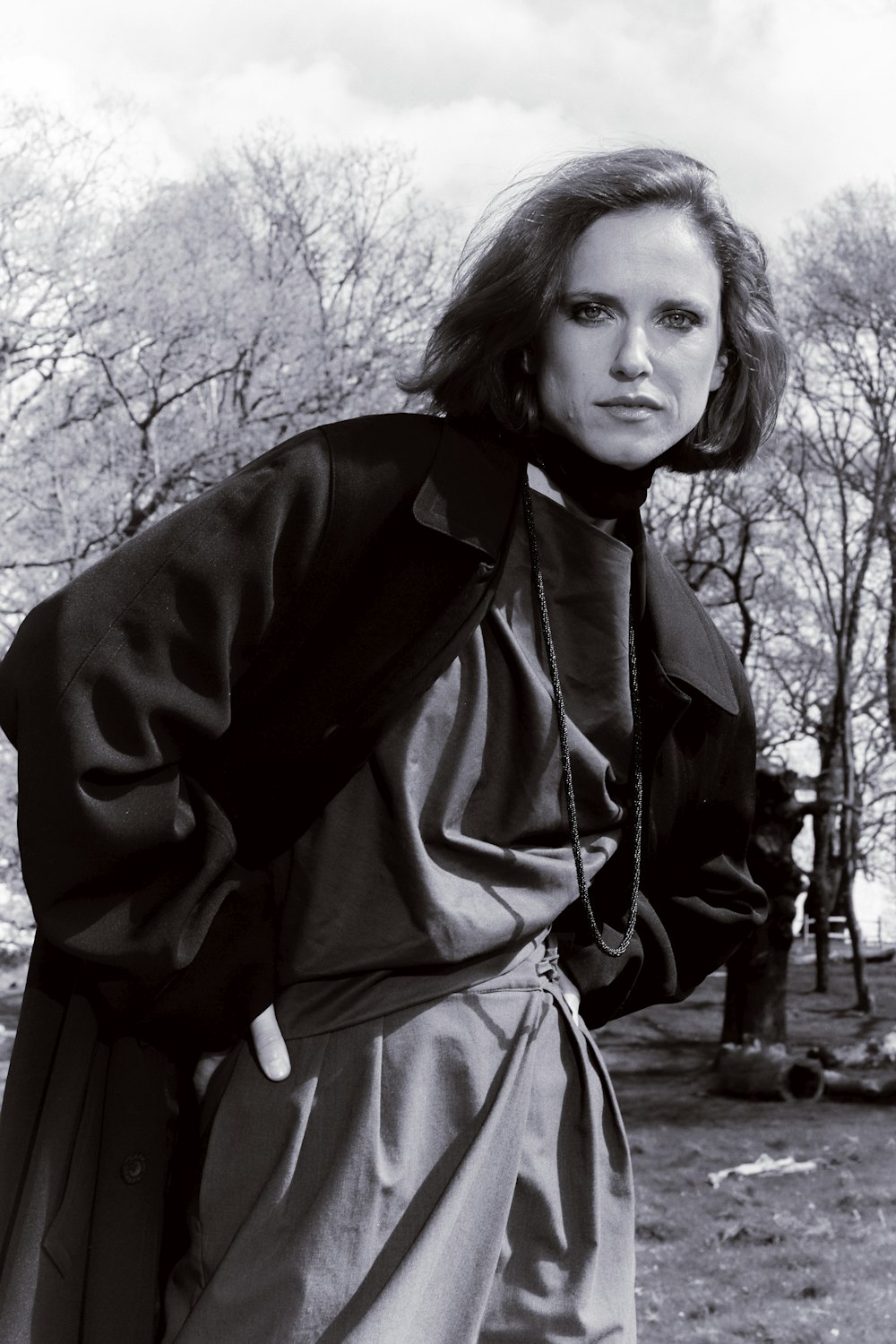 a black and white photo of a woman in a trench coat