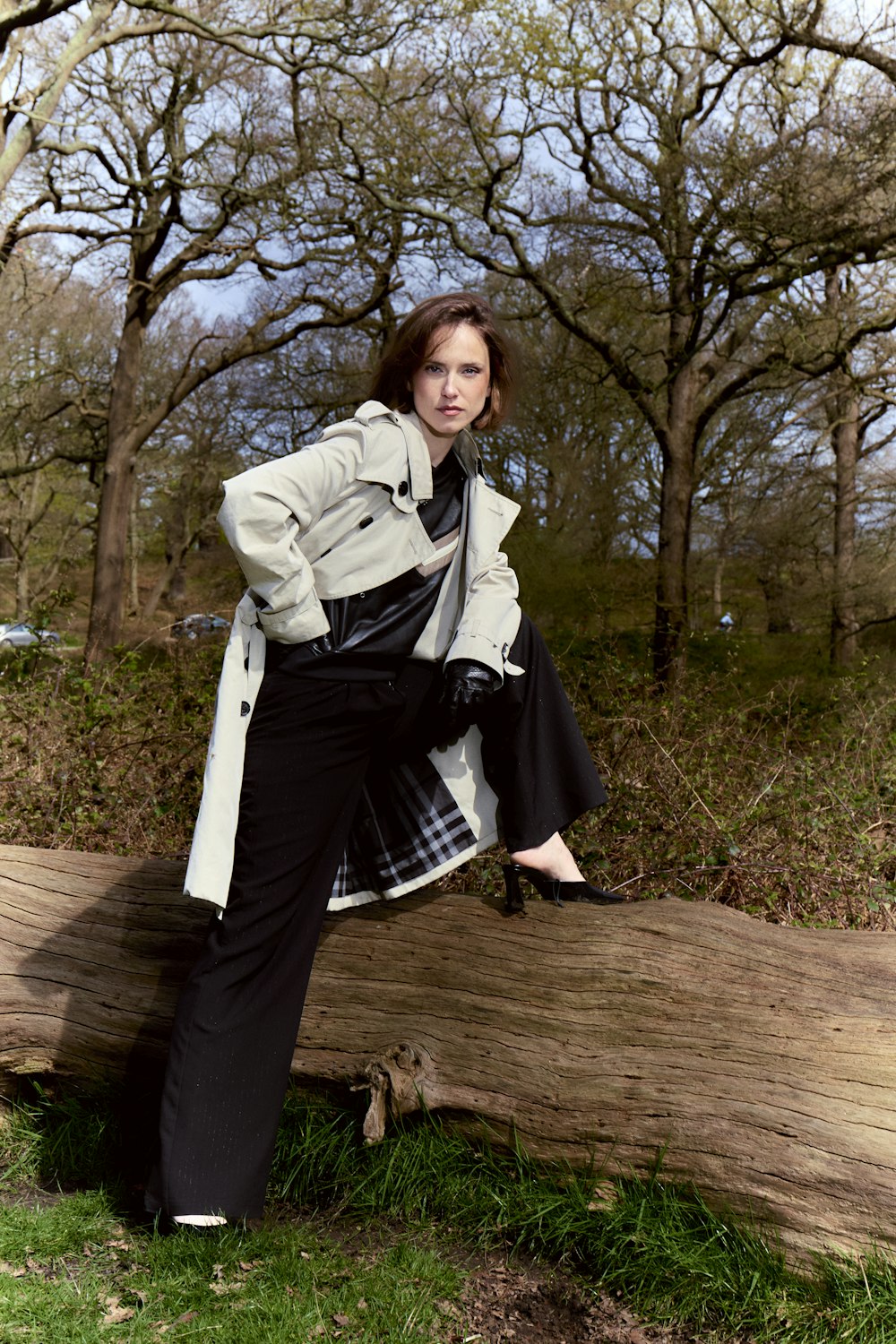 a woman leaning on a log in a park