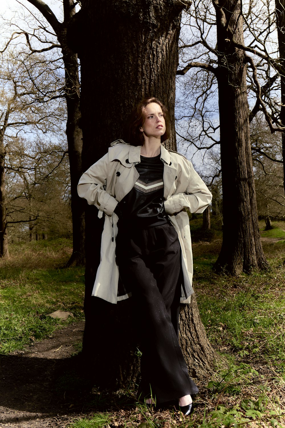 a woman leaning against a tree in a park