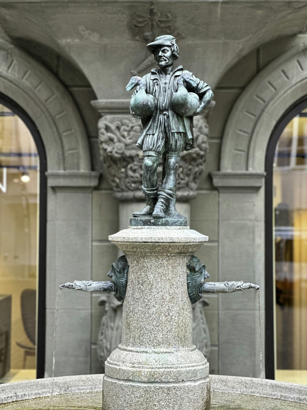 une statue d’un homme debout au sommet d’une fontaine