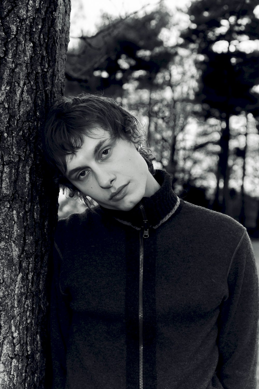 a man standing next to a tree in a forest