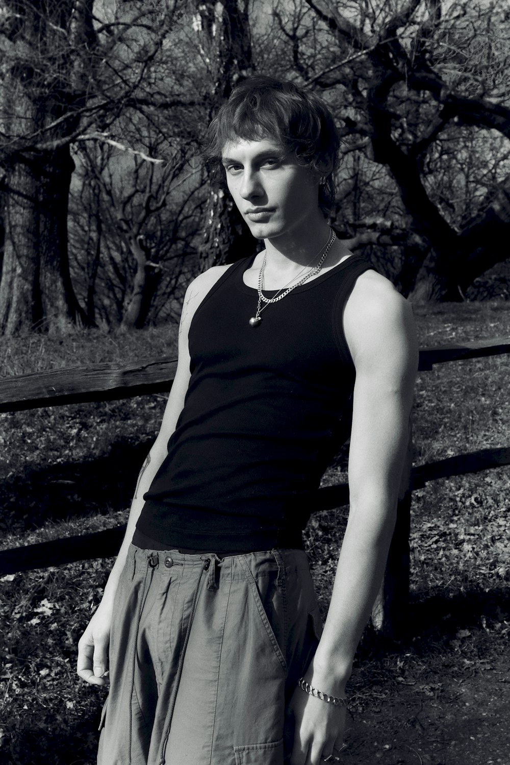 a young man standing in front of a wooden fence