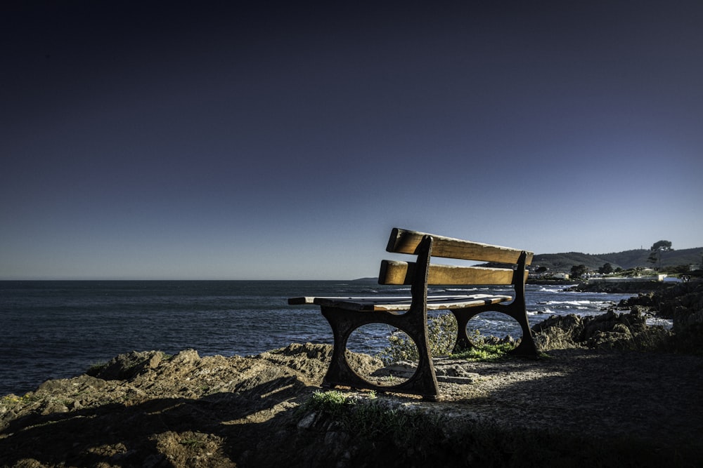 a wooden bench sitting on top of a cliff near the ocean