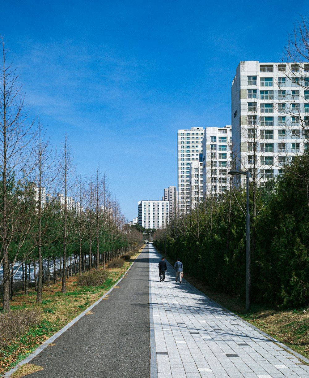 a couple of people walking down a street next to tall buildings