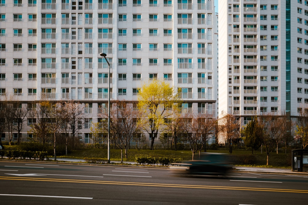 a car driving past a tall white building