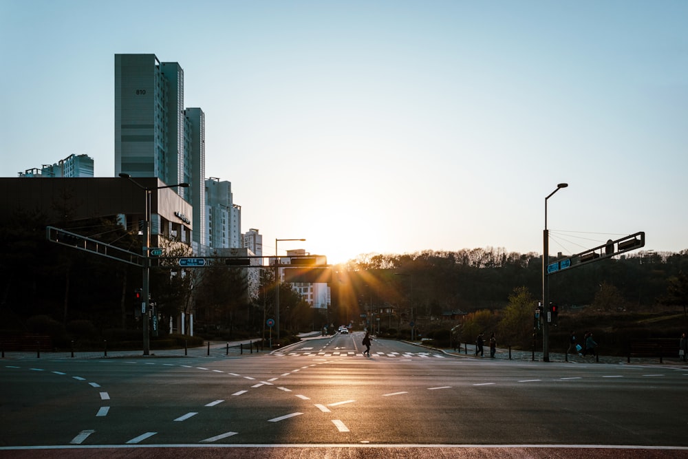 a person walking across a street at sunset